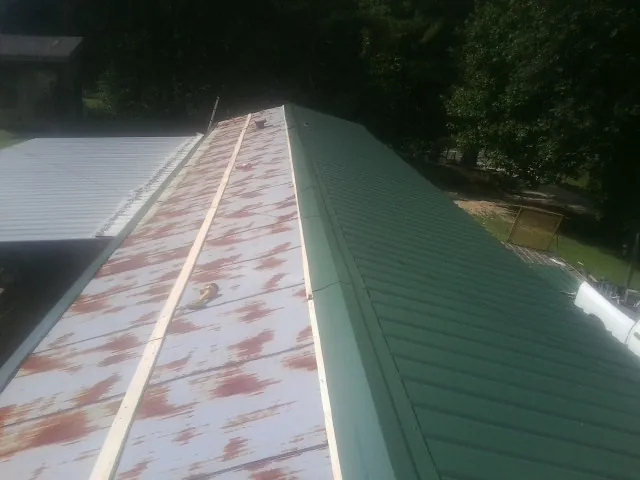 Old rusted panels beside newly installed green metal roofing — Wind Damage Roof Repair by Roofing Brothers in Winnetka