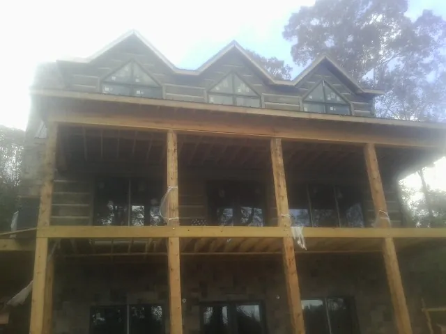 Dormers and porch framing on a large log home under construction — Roof Coating work by our crew in Winnetka