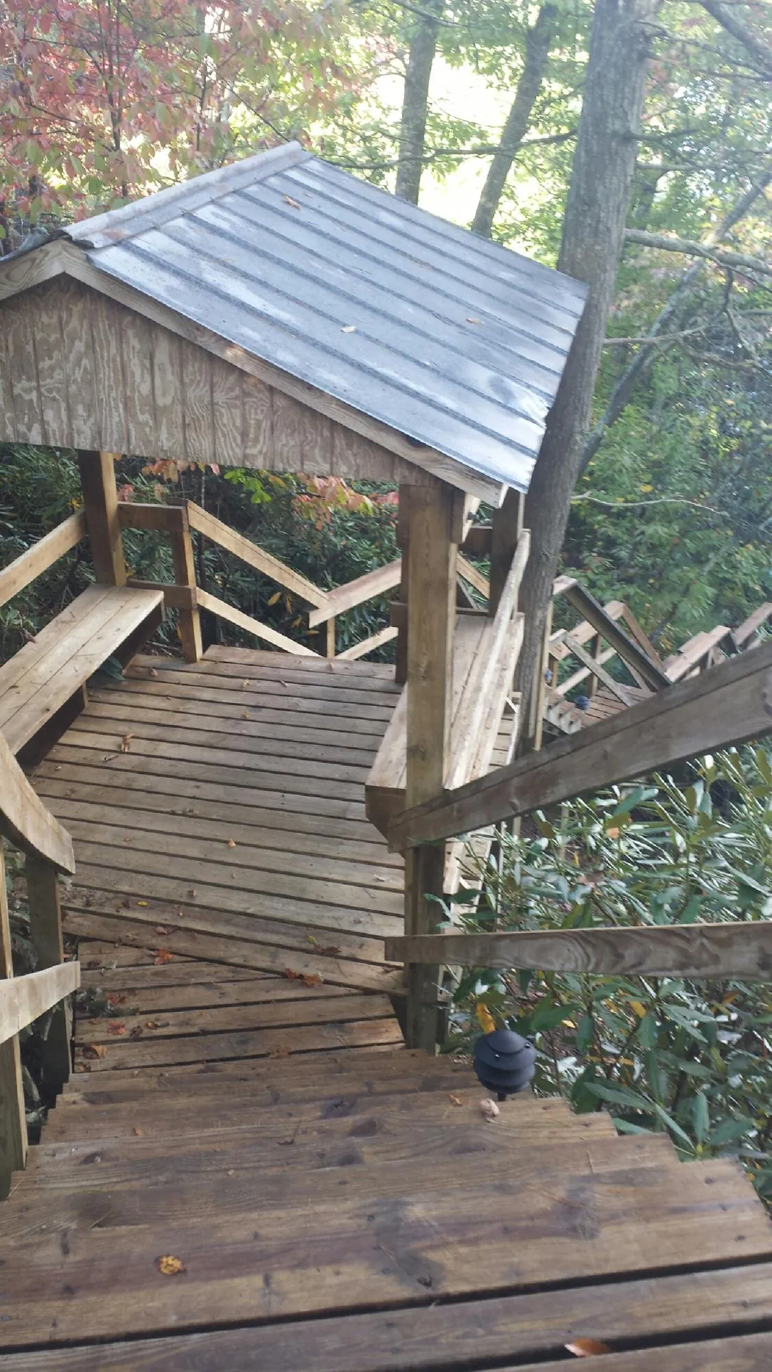 Metal roofed shelter over wooden steps on a wooded walkway — Skylight Repair & Installation work by our crew in Winnetka