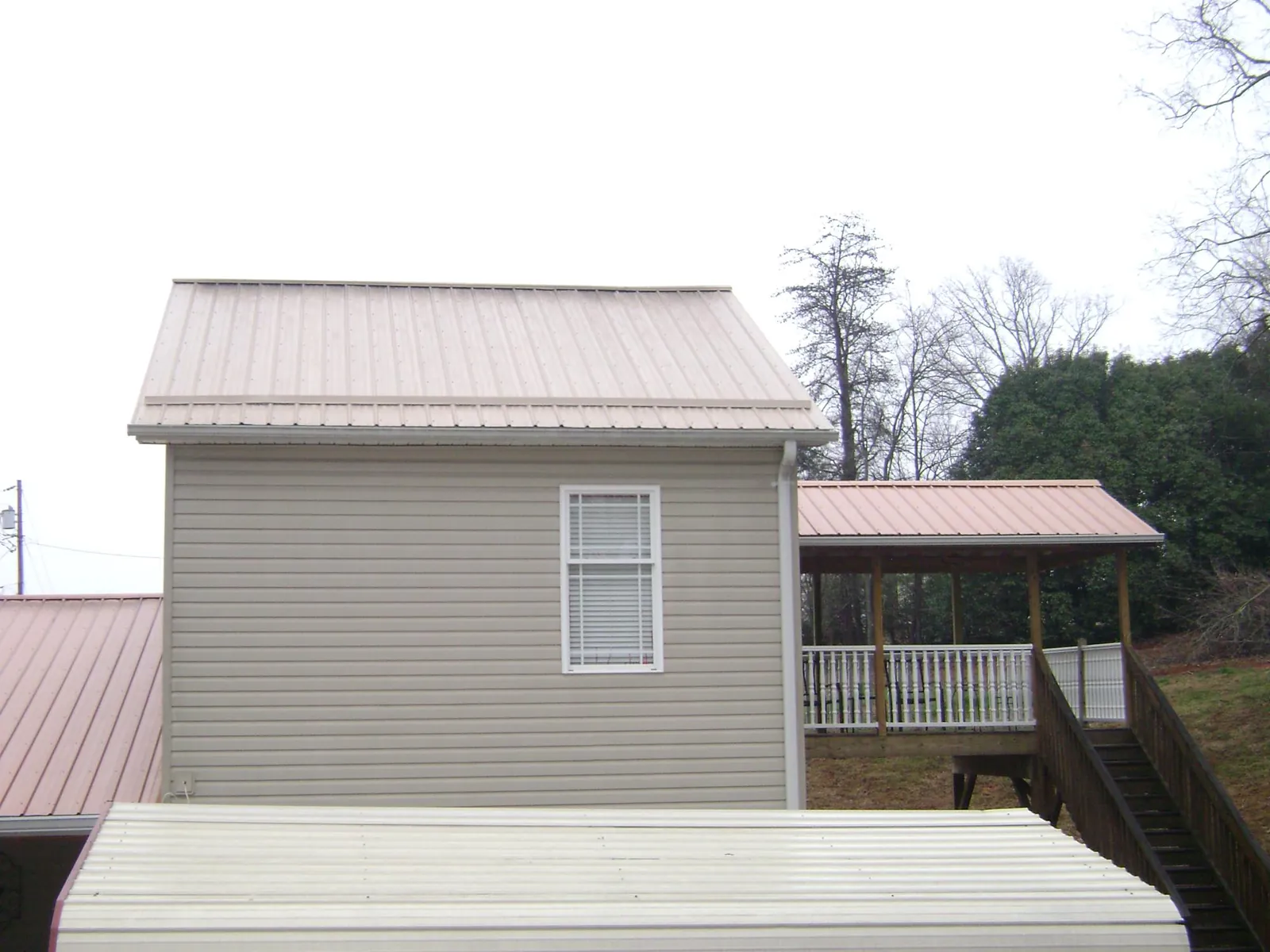 Tan metal roofs on a two story addition and attached porch, from a Roof Replacement job in Winnetka