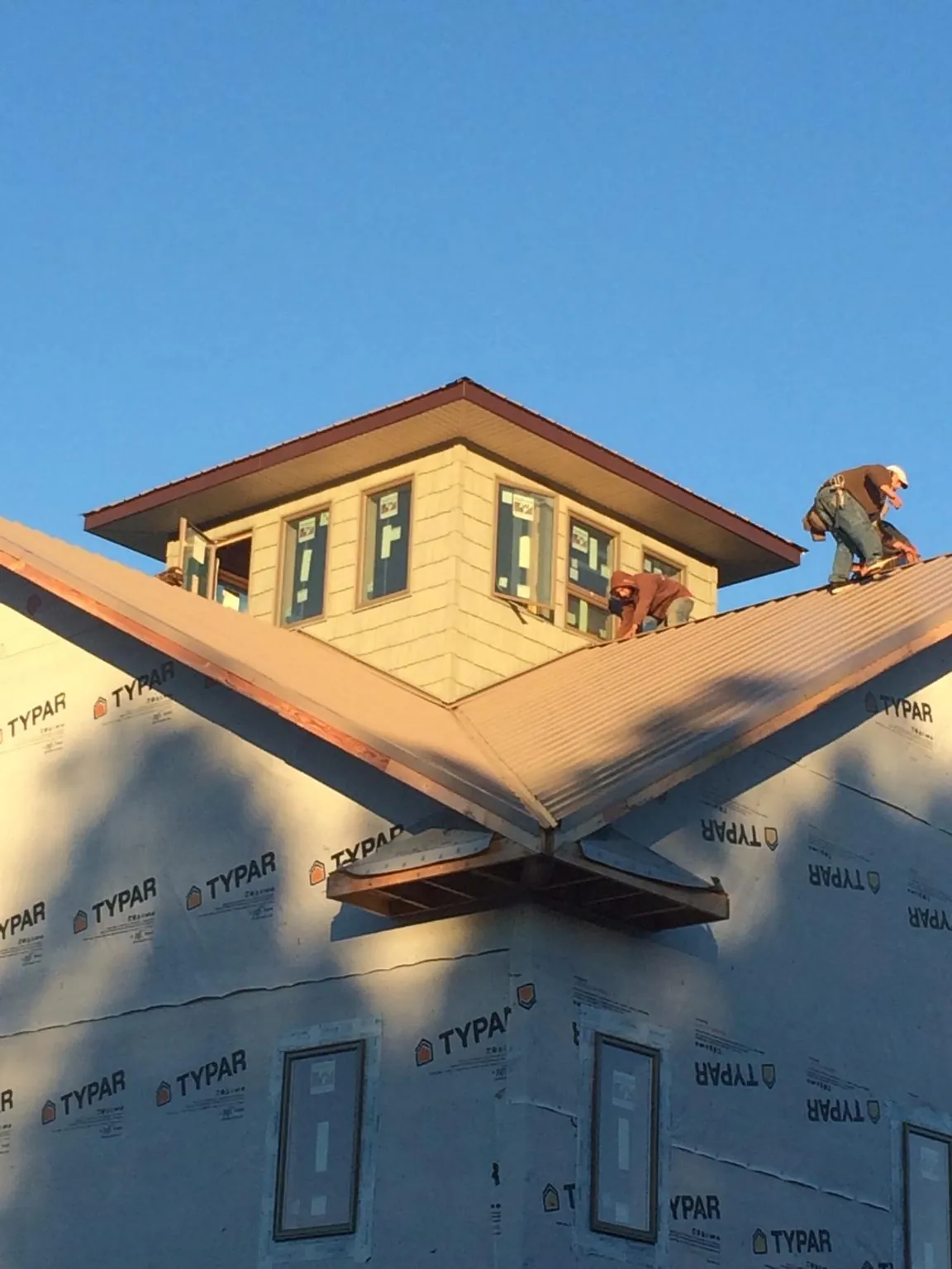 Roofers working around a rooftop cupola on a new metal roof at sunset — Roof Waterproofing in Winnetka by Roofing Brothers